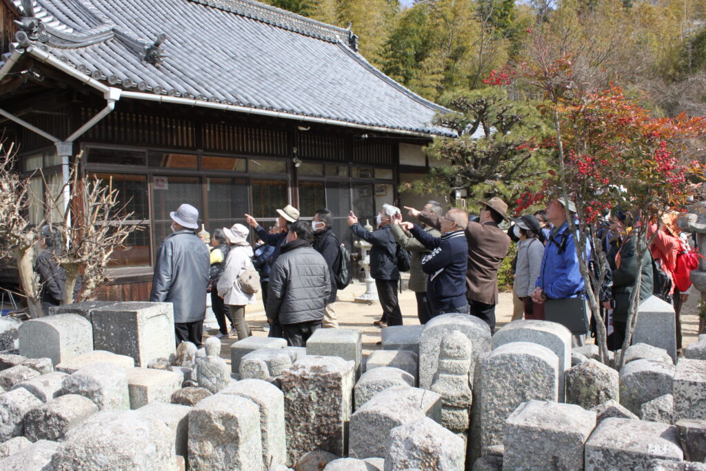 常楽院で説明を聞く参加者。手前には中世からの石造物がいっぱい。